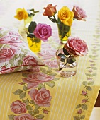 Different-coloured roses in glasses (table decoration)