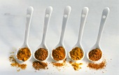 Five different curry powders in porcelain spoons