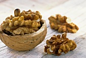 Walnut in half shell and two shelled walnuts on wooden background