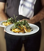 Man holding plates of pumpkin with melted cheese and rocket