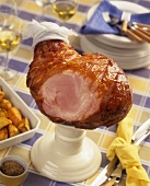 Roast ham, partly carved, with roast potatoes
