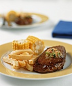 Gegrilltes Steak mit Knoblauchbutter, Pommes und Maiskolben