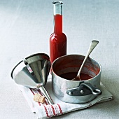 A bottle of rose hip syrup with pan and funnel