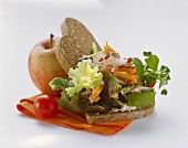 Wholemeal bread with a mixed leaf salad, vegetables and an apple