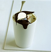 A cup of vanilla ice cream with chocolate sauce