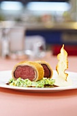 Saddle of venison wrapped in bread with cream savoy cabbage and celery chips