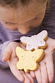 A little girl holding two butterfly biscuits