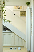 Looking at a white staircase with built in cupboard in a niche and with dog dishes