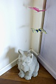 A stone animal figure and a paper butterfly in a corner of a room