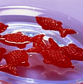 Rote Plastikfische in einer Wasserschale als Tischdeko