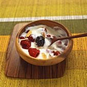 Yoghurt with red berries, honey and almonds in wooden bowl