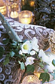 Christmas roses in decorative tube lying on a cushion