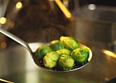 Taking cooked Brussels sprouts out of pan with slotted spoon