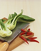 Pak choi & chillies on wooden board with Asian knife