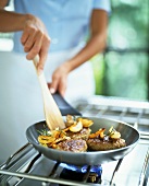 Burgers with vegetables and rosemary in a frying pan