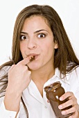 Young woman eating chocolate spread from the jar