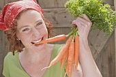 Young woman biting into freshly picked carrot