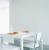 Ein weißer Esstisch mit orangem Geschirr gedeckt im sterilem Raum