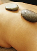 LaStone-Therapie: Warme Steine auf dem Rücken einer Frau