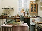 Frau beim Abwaschen in einer amerikanischen Landhaus-Küche mit Spülbecken unter dem Fenster