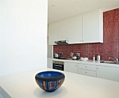 Blick durch Durchreiche in einer Weißen Küche mit roter Glassteinwand