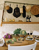 A culinary arrangement featuring fresh vegetables, hanging baskets and pans
