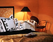 Warmes Licht einer brennenden Nachttischlampe in orangefarbener Schlafzimmerecke