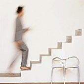 Frau geht auf einer freischwingenden Treppe nach oben