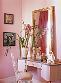 Ein rosafarbenes Zimmer mit rosa Kosmetiktisch und vergoldeter Spiegel