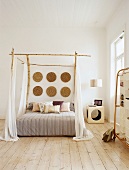Ein Himmelbett mit Bambusstäbe und weiße Vorhänge im Schlafzimmer