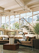 Mann und Baby auf braune Eckcouch im offenem Wohnraum mit Panoramafenster und Holzbalkendecke