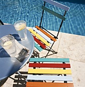 Two glasses on water on table next to pool