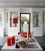 Rote Kerzen und rustikales Geschirr als Dekorationsobjekte eines streng symmetrischen Raums