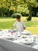 Junge an gedecktem Tisch im Freien stehend