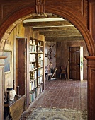 Altertümliche, rustikale Diele mit Bücherwand und Backsteinfliesen