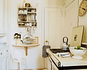 Kleine, einfache Küche mit weißem Einbauschrank, einem altmodischen Gasherd und einem halbrunden Klapptisch
