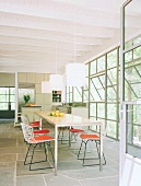 Lichterfülltes Esszimmer mit langem Esstisch und moderner Küche mit Küchenblock im Hintergrund