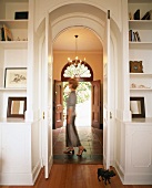 View through open living room doors into corridor with front door at far end