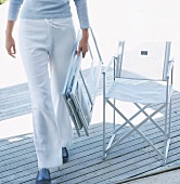 Woman carrying folded garden chair