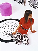 Young woman wearing striped tights sitting on rug