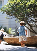 Boys playing in sand around dugout canoe