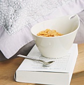Eine Schüssel Cornflakes mit Löffel auf einem Buch