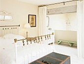 Schlafzimmer mit altem Metallbett und Ankleideraum hinter einem Vorhang