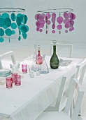 Weißer Esstisch mit bunten Paillettenleuchten und Gläsern