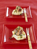 Tuna fish on mashed potatoes in red dishes