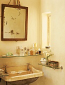 Antiker Spiegel und Waschbecken mit Parfumfläschchen auf einem Glaswandboard