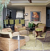 Wohnzimmer mit Sesseln aus Rattan und Küchentheke in Naturtönen