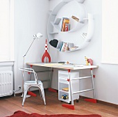 Ein Schreibtisch mit Tolix Stuhl und ein spiralförmiges Wabdregal in der Ecke eines Kinderzimmers
