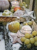 Plastik-Früchte mit Kunstschnee und Windlicht zu Weihnachten