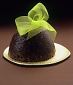 Christmas pudding with green bow on gold plate